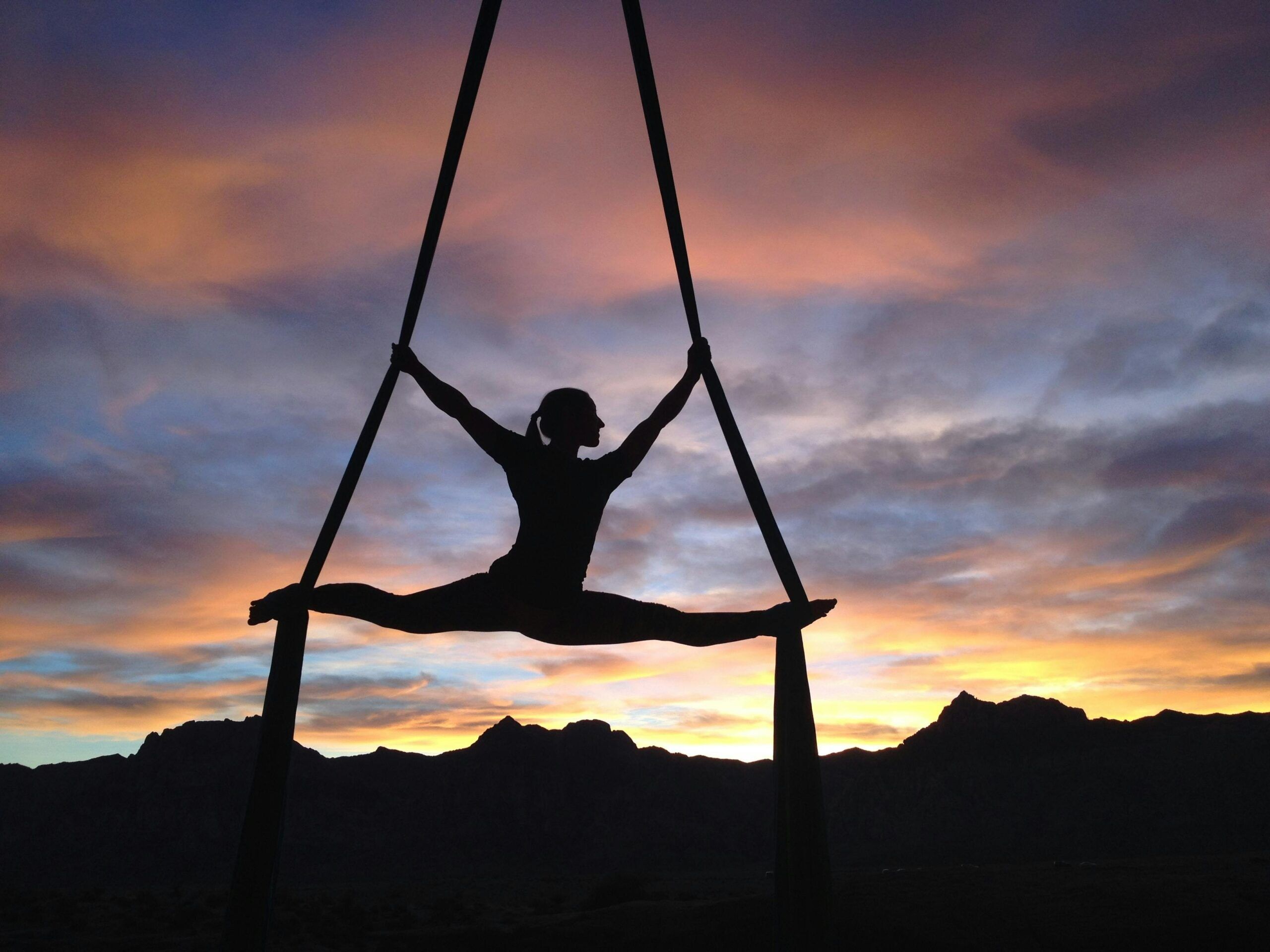 Beginner performing aerial yoga pose using hammock at home